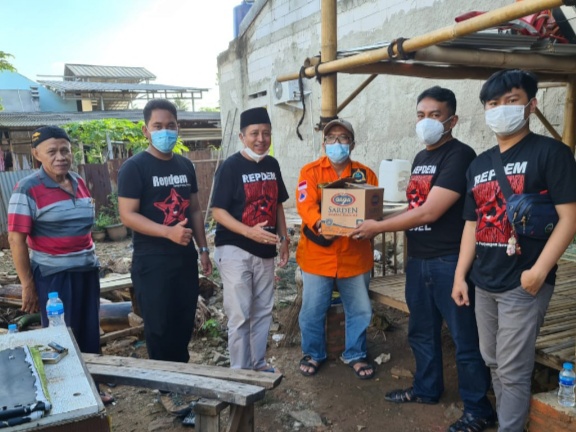 Ketua Repdem Kota Tangerang Selatan, Ronald Adelius saat memberi bantuan kepada warga yang kena banjir ( kaos hitam )